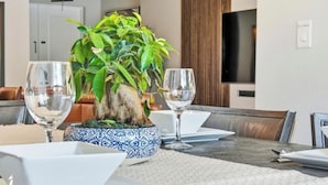 A dining area with a table set for two, a decorative plant centerpiece, and a television mounted on the wall.