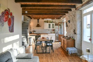 A modern kitchen with a wooden floor, white cabinets, and a dining area with a table and chairs.