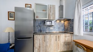 A compact kitchen with a refrigerator, microwave, and wooden cabinets.