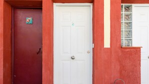 A red door with a small decorative plate, a white door with a number '2' sign, and a window with frosted glass panels.