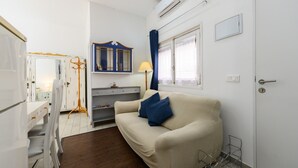 Un espace de vie compact comprenant un canapé, une petite table, une lampe et une armoire.