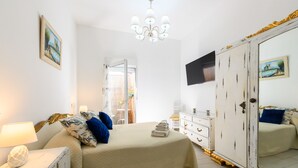 Une chambre à coucher avec un lit, une commode, un miroir, une télévision et un lustre.