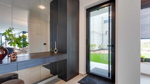 A modern entryway with a dark wooden door, a glass door leading outside, and a small indoor garden with a plant and candles.