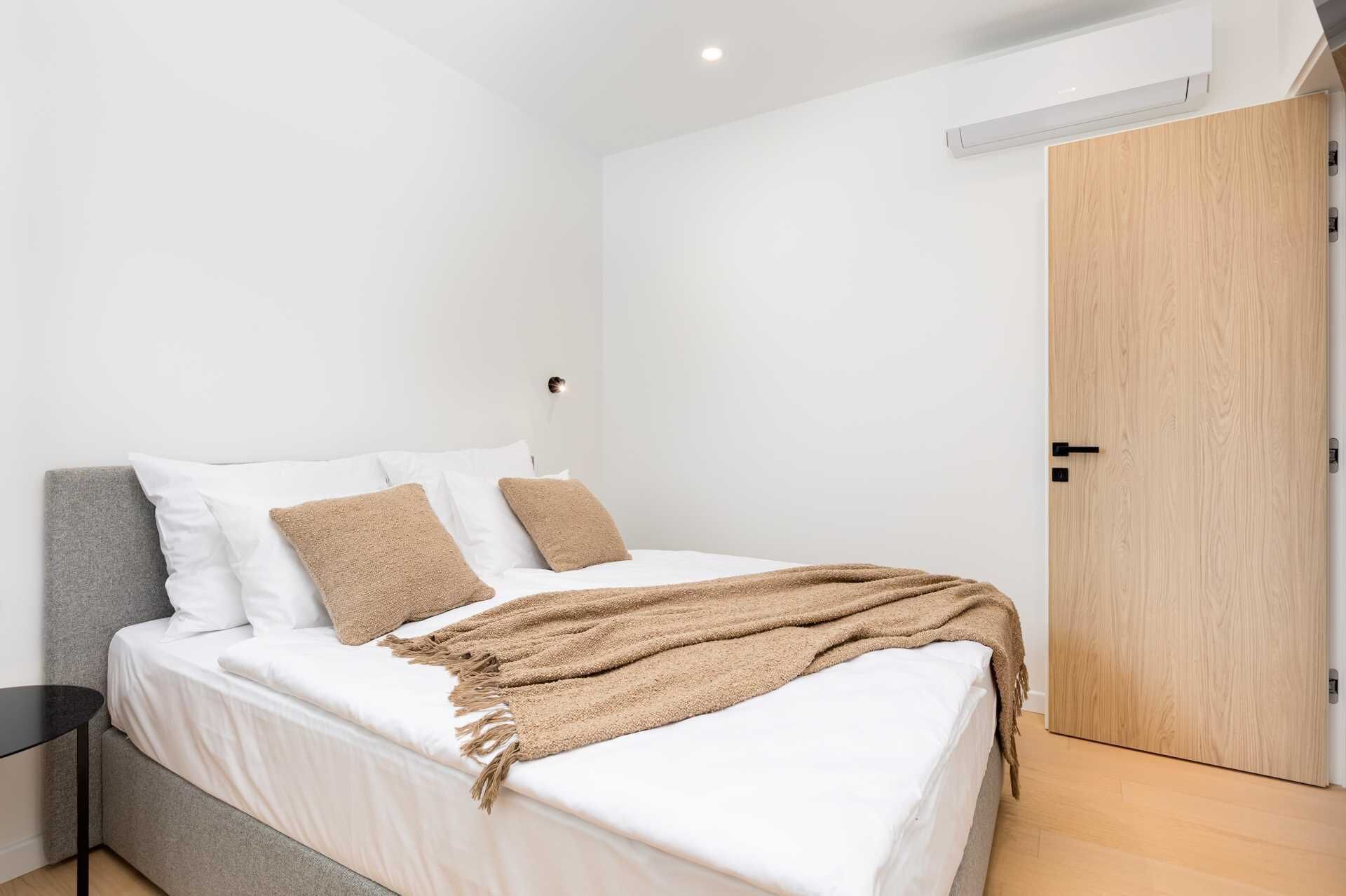 A modern bedroom with a bed, pillows, and a blanket.