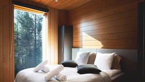 A bedroom with a bed, pillows, and a window with a view of trees.