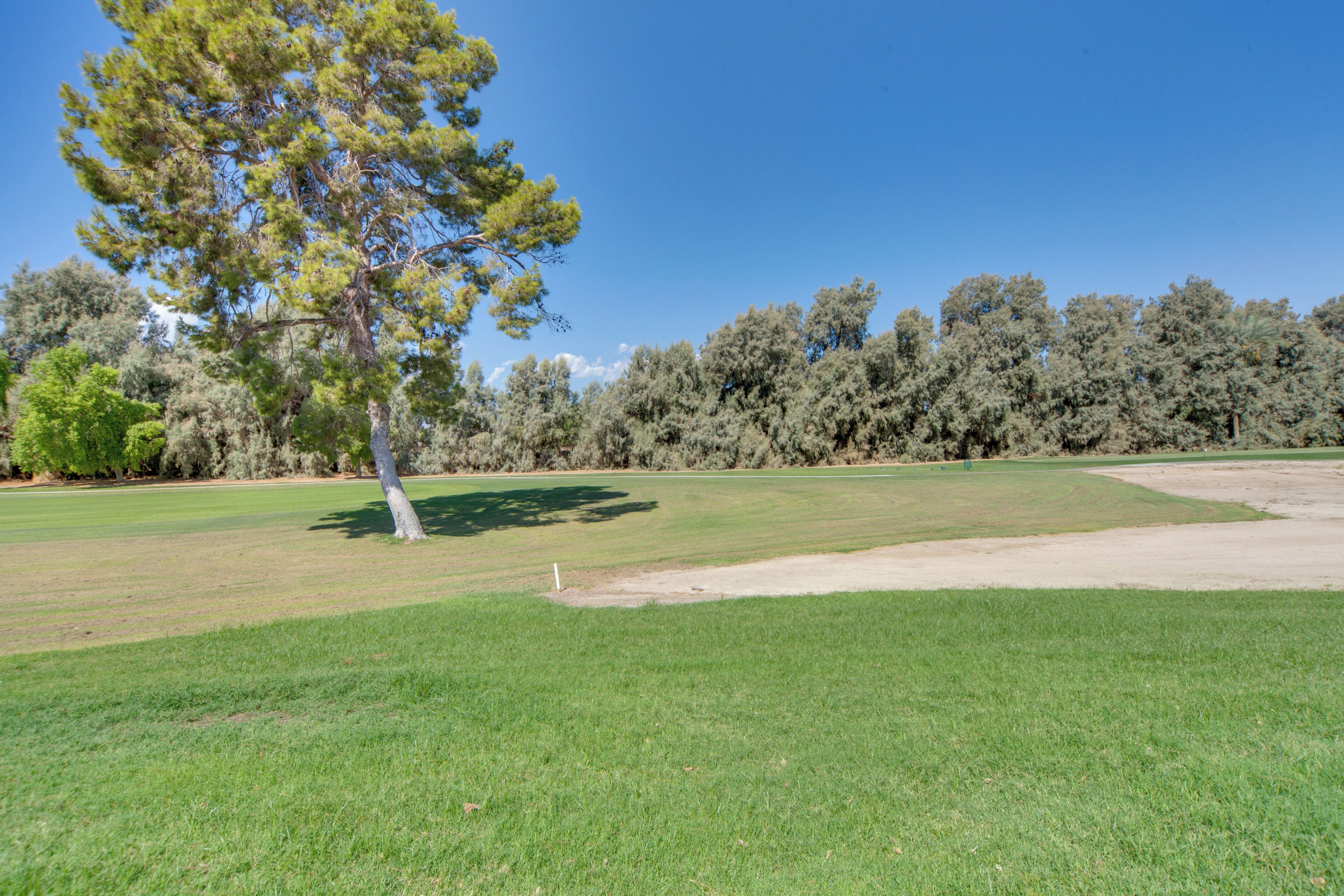 Un parcours de golf avec un ciel dégag é, un gazon bien entretenu et une rangée d’arbres en arrière-plan.