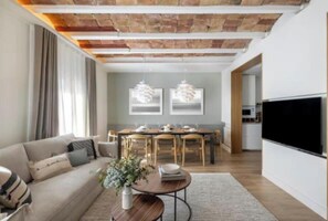 Een moderne woonkamer met een bank, salontafel en eethoek.