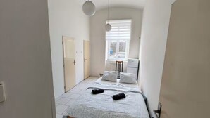 Un dormitorio pequeño y estrecho con una cama, dos almohadas y una ventana.