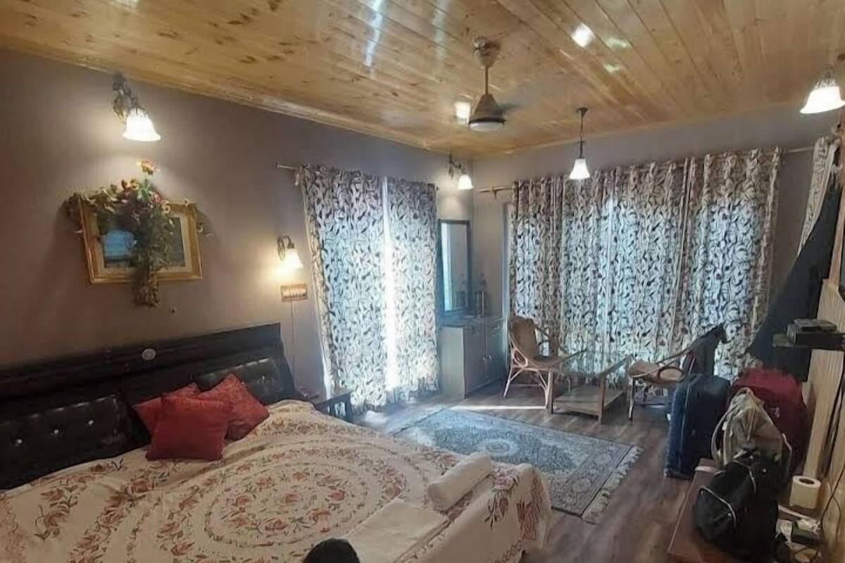 A room with a large bed, a desk, and a chair.