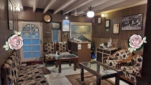 A living room with patterned sofas, a glass coffee table, and a wooden cabinet. - Blooming Dale (Srinagar)
