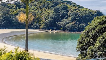 Une plage à l’eau claire, un rivage sablonneux et, en arrière-plan, une colline couverte d’une végétation luxuriante.