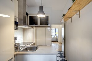 Une cuisine moderne dotée d’un îlot central, d’un évier en acier inoxydable et de luminaires suspendus.