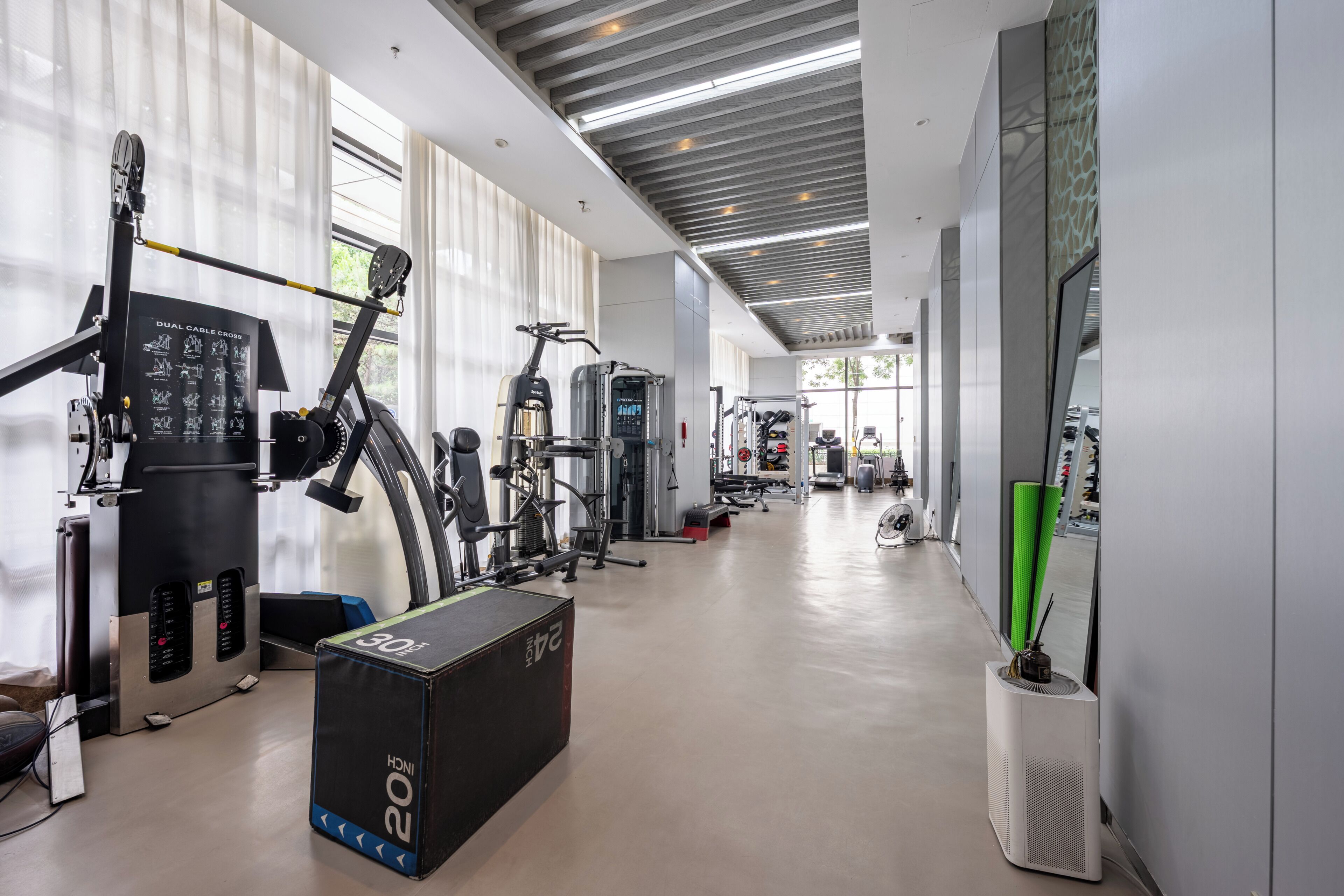 A gym with exercise equipment, a large window, and a ceiling with exposed beams.