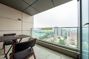 A balcony with a city view, a table, and chairs. - Beijing Shimao TNT Apartments (Beijing)