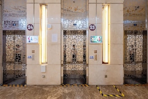 An elevator with decorative panels, numbers 24 and 25, and a digital display.