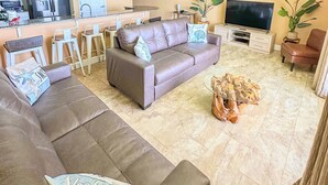 Un salon avec un canapé, une table basse, un téléviseur et un ventilateur de plafond.