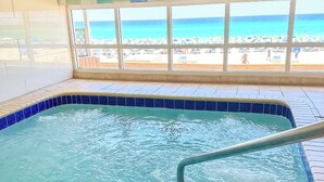 Une piscine intérieure avec vue sur la plage, grâce à de grandes baies vitrées.