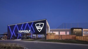 Un bâtiment moderne arborant un logo TOPGOLF bien visible et un symbole représentant un club de golf.