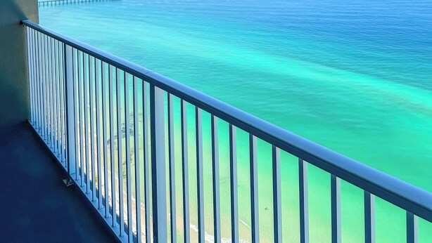 Un balcon avec vue sur l’océan et une jetée.
