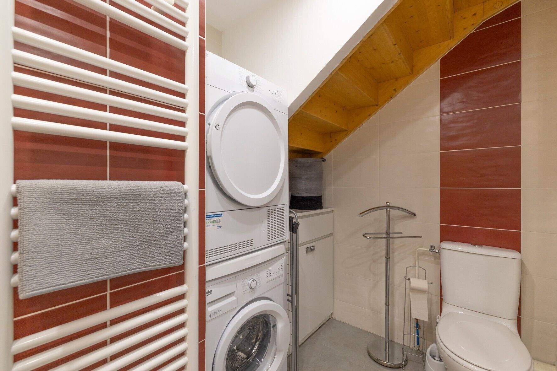 A compact bathroom with a washing machine, a toilet, and a shower.