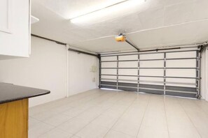 Eine Garage mit geschlossenem Garagentor, einer Deckenleuchte und einem gefliesten Boden.