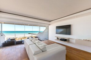 Un salon moderne avec un grand téléviseur, un canapé et une vue sur la plage.
