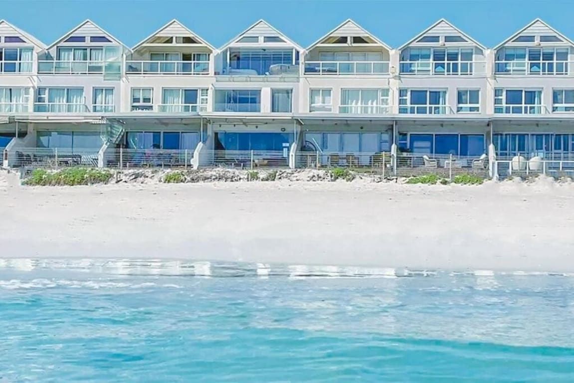 Un hotel frente al mar con varios niveles, balcones y vista despejada al océano.
