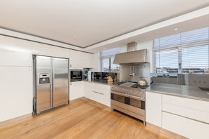 Eine moderne Küche mit Edelstahlgeräten, Holzboden und großen Fenstern.