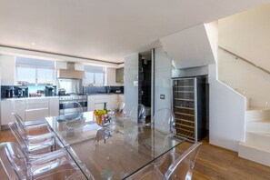Eine moderne Küche mit einem Glastisch und Stühlen, einem eingebauten Ofen und einem Kühlschrank.