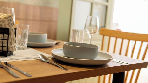 Une table à manger avec un saladier, une cuillère et de la verrerie.