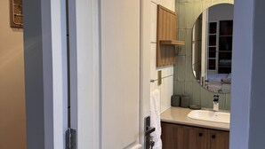 Une salle de bain avec une porte blanche, des meubles en bois, un lavabo et un miroir.