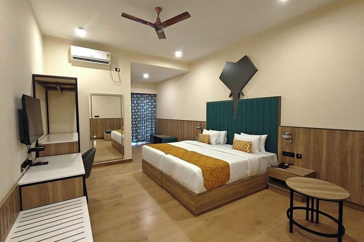Une chambre d’hôtel moderne équipée d’un lit, d’un bureau, d’une chaise, d’une télévision et d’un ventilateur de plafond.