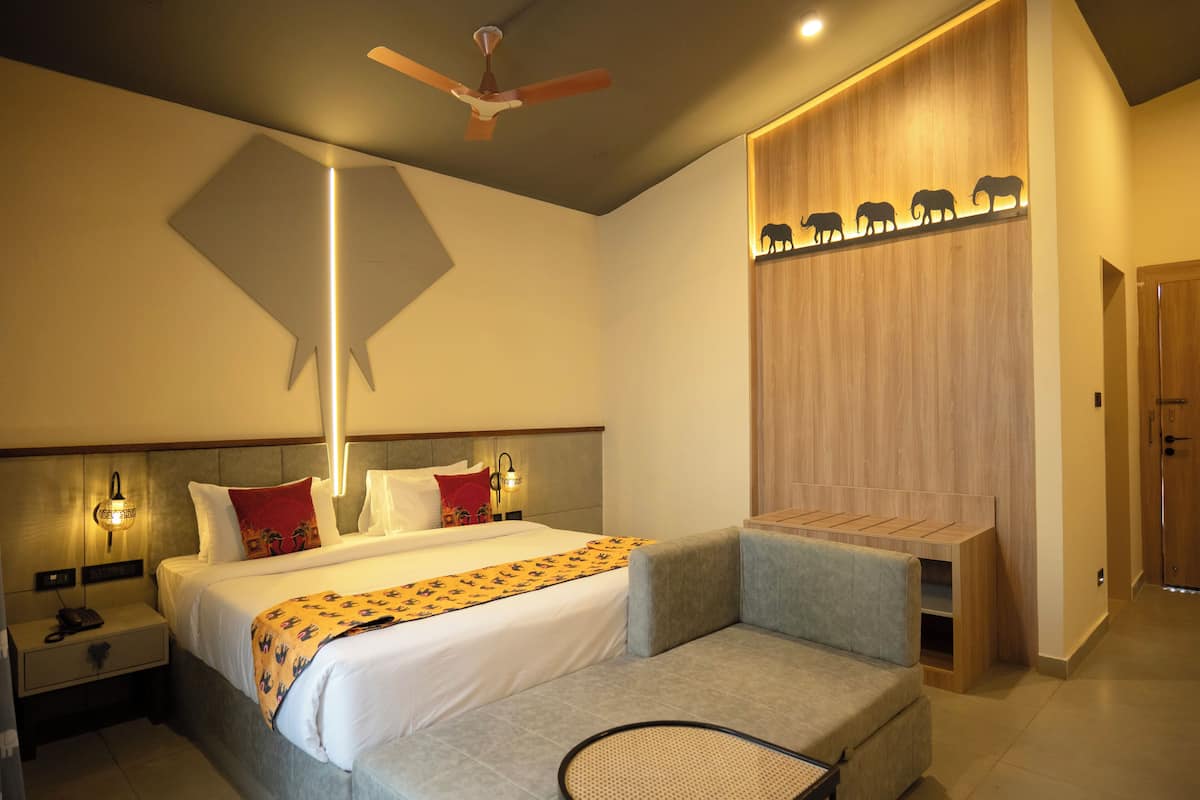 Une chambre d’hôtel moderne équipée d’un lit, de tables de chevet, d’un bureau, d’un ventilateur de plafond et d’une étagère murale ornée de silhouettes d’animaux.