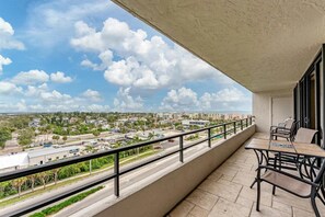 Un balcon donnant sur un paysage urbain, une table avec des chaises et une rambarde.