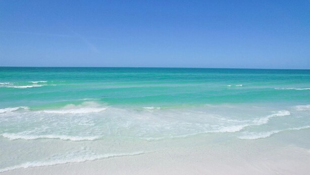 Ein Strand mit klarem türkisblauem Wasser und weißem Sand.