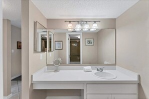 Une salle de bain moderne avec un grand miroir, un lavabo blanc et un espace douche.