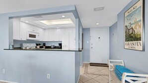 A modern kitchen with white cabinets, a black countertop, and a recessed ceiling light.