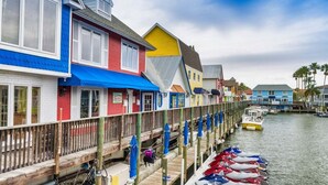 A waterfront property with colorful buildings, a wooden dock, and boats.