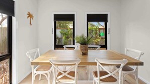 A dining area with a wooden table and white chairs, two doors leading outside, and a potted plant on the table. - Stylish Townhouse 2 Min Walk to Beach & Shops (Cowes)