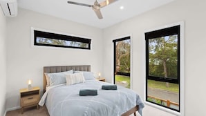 A bedroom with a bed, a nightstand, a ceiling fan, and large windows. - Stylish Townhouse 2 Min Walk to Beach & Shops (Cowes)