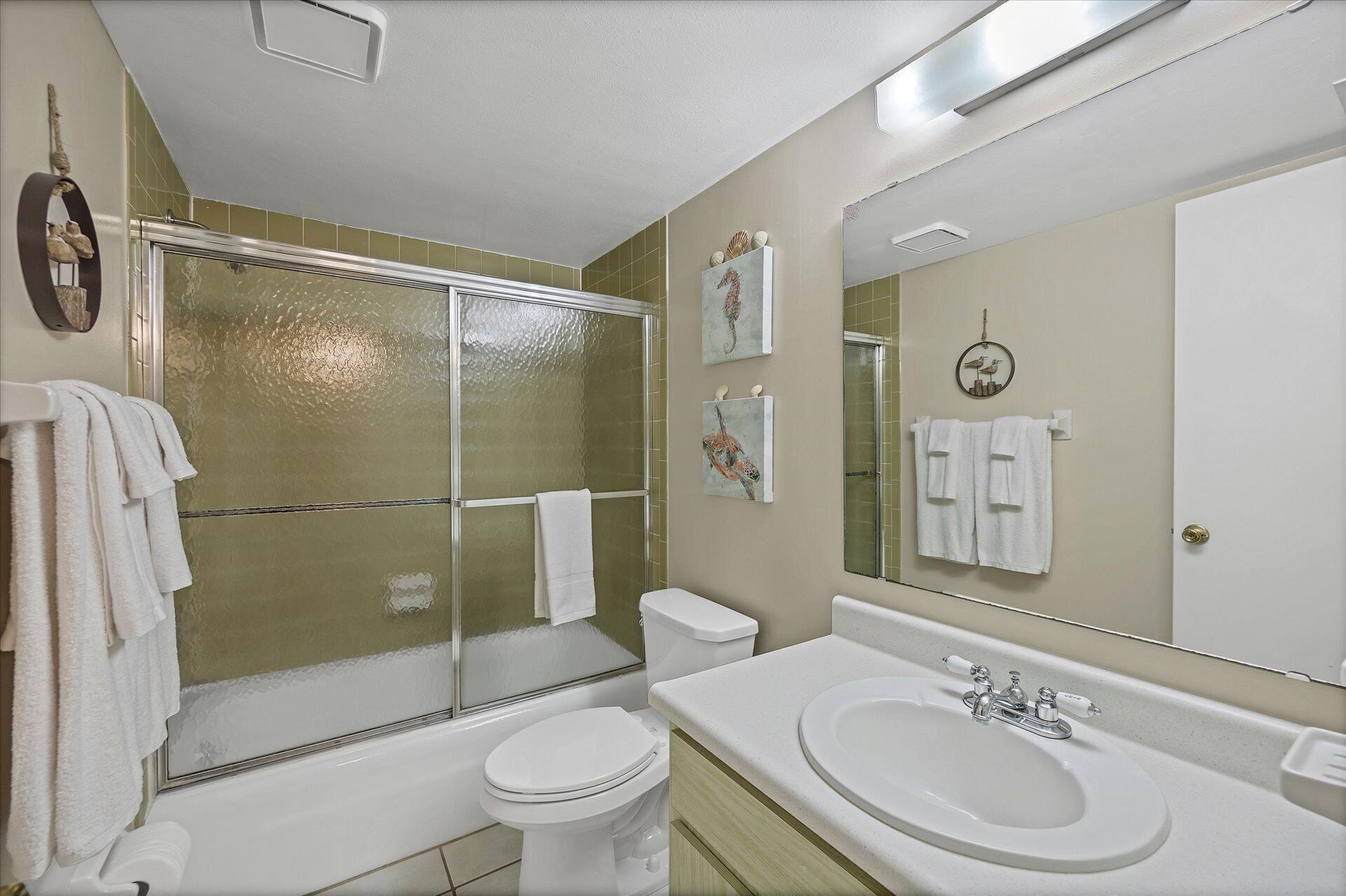 Une salle de bain avec une douche à parois de verre, des toilettes, un lavabo avec un miroir et des serviettes accrochées au mur.