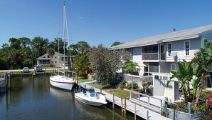 A marina with a sailboat docked, a house with a balcony, and a dock extending into the water. - Lemon Bay Waterfront Condo w Patio (Englewood)