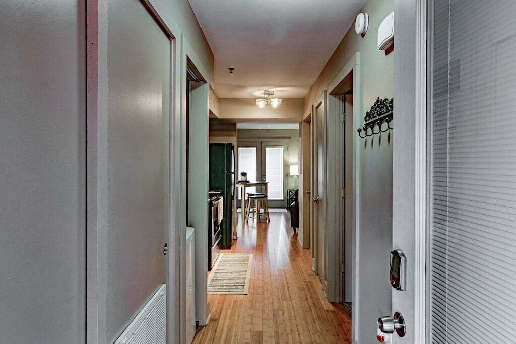 Un couloir doté d’un plancher en bois, de murs blancs et d’une porte équipée d’une serrure de sécurité.