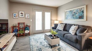 A living room with a grey sofa, a coffee table, a rug, and a painting on the wall. - Loft #211 (540 N 2nd St) (Clarksville)