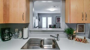 A modern kitchen with wooden cabinets, a stainless steel sink, and a coffee maker. - Loft #304 (540 N 2nd St) (Clarksville)