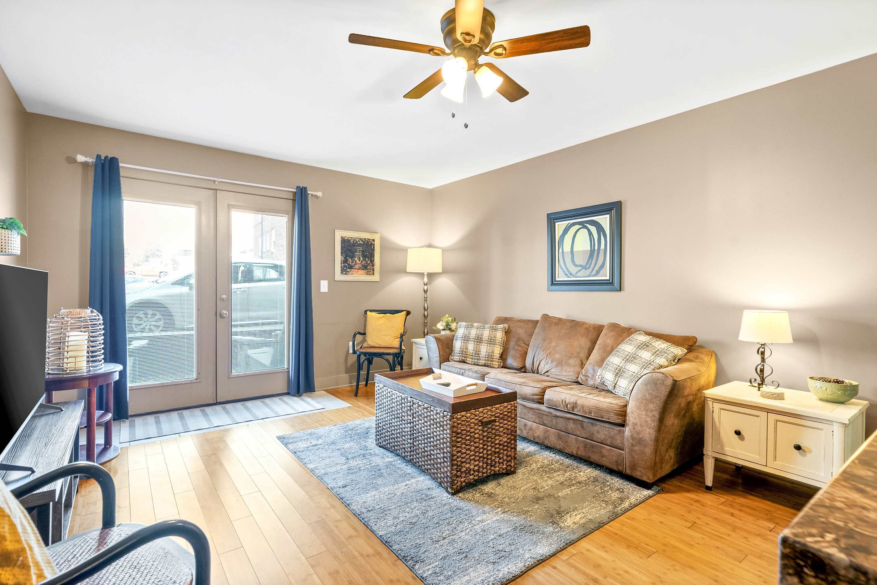A living room with a sofa, coffee table, and side table, a ceiling fan, and a view through a glass door.