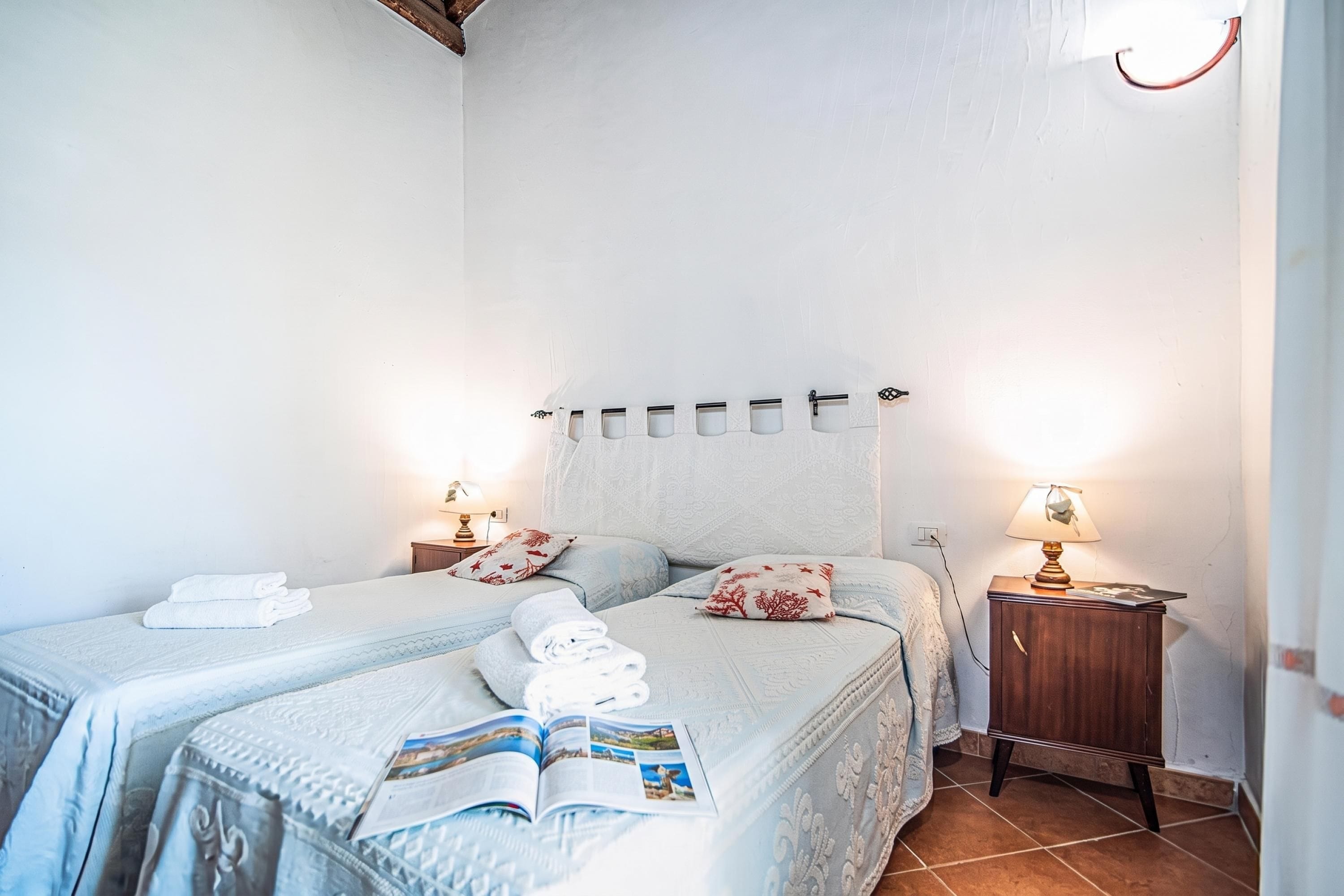 Een slaapkamer met twee bedden, een nachtkastje en lectuur op het bed.