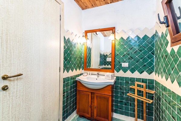 Un baño con un armario de madera, un lavabo y un espejo.
