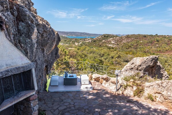 A stone staircase leading to a terrace with outdoor seating and a view of a coastal landscape. - Villa La Licciola (Arzachena)
