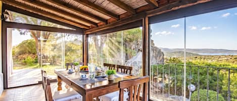 Comedor con mesa lista para cuatro, con vista a un paisaje pintoresco.
